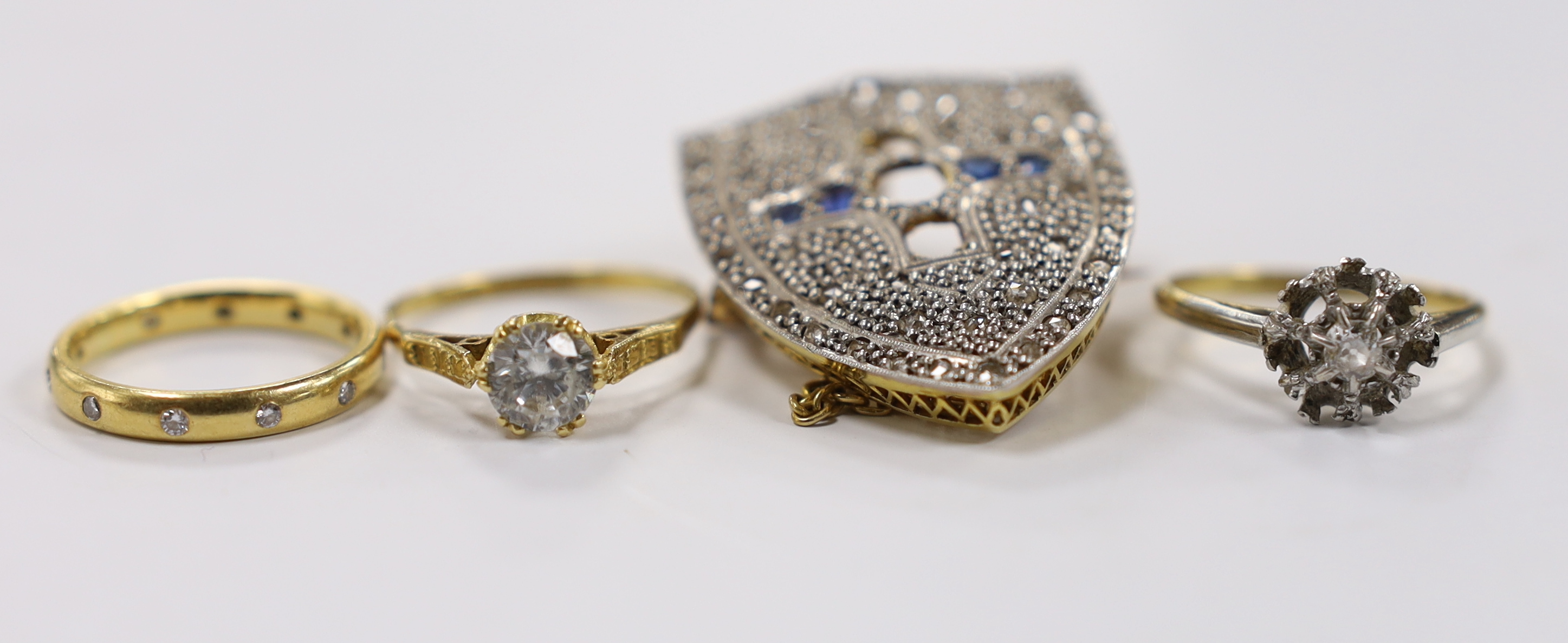 A late 19th century yellow metal, rose cut diamond and sapphire cluster set shield shaped brooch (three stones missing), 35mm and three rings including modern 18ct gold and gypsy set eternity, an 18ct and single stone di